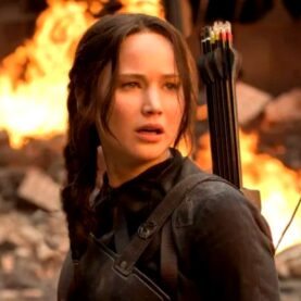 Katniss Everdeen em cenário caótico de Jogos Vorazes