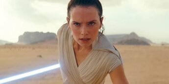Daisy Ridley com sabre de luz azul em deserto, em Star Wars