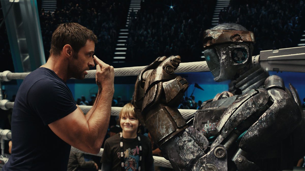"REAL STEEL" RS-FF-012R Charlie Kenton (Hugh Jackman, left) gives instructions to Atom while his son, Max (Dakota Goyo) looks on in DreamWorks Pictures' action drama "Real Steel". ©DreamWorks II Distribution Co., LLC. ÊAll Rights Reserved.